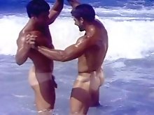 2 studs on beach caress their bodies before doing blowjobs